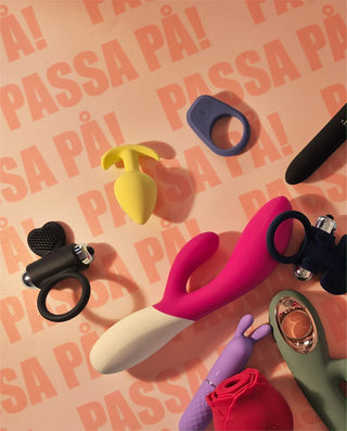 Närbild på färgglada sexleksaker i kroppssäkert silikon, inklusive vibratorer och buttplugs, arrangerade på ljus bakgrund