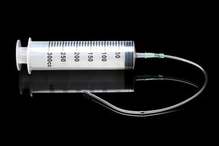 En 300 ml spruta W Tube, som liknar en hygienisk lösning, vilar elegant på en reflekterande svart yta.
