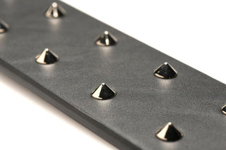 Närbild av E-Stim Spiked Paddles svarta veganska läderrem med jämnt fördelade metalliska kondubbar.