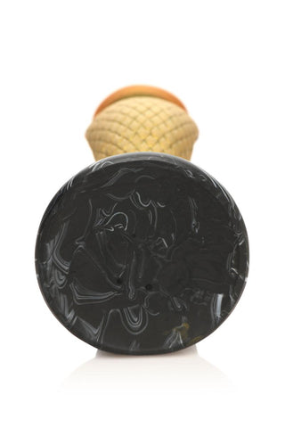En närbild av en abstrakt, strukturerad svart yta med en suddig våffelkonform i bakgrunden, som påminner om den S-formade designen av Golden Mamba Dildo.