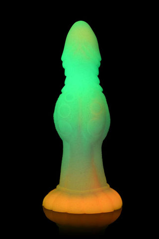 En livlig, glödande Alien Dildo gjord av ftalatfri silikon som visas på en blank svart yta.
