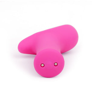 Det rosa, abstrakt formade föremålet med två små hål på framsidan liknar en Lovense Ambi och är elegant inställt mot en vit bakgrund.