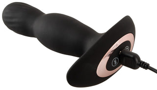 Anos Finest Buttplug Med Fjärr är en svart vibrerande massageapparat i silikon med roséguldaccenter, med en ergonomisk design och en laddningskabel.