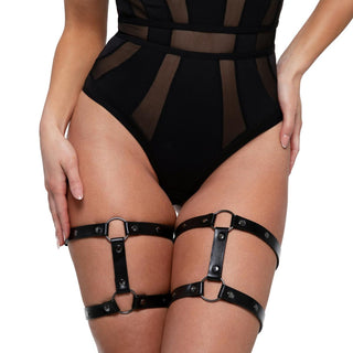 Mot en vanlig bakgrund förkroppsligar en person i en bodysuit i svart mesh och Bedroom Fantasies Lår Sele med justerbara remmar fantasins essens.