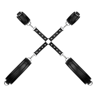 Upptäck Cuffs & Hogtie Set, med svarta läderhållare i en X-form, perfekt för att utforska dina sovrumsfantasier, visad på en vit bakgrund.