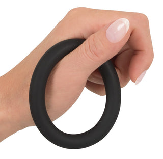 En hand håller Black Velvet Cock & Ball Loop mot en vit bakgrund.