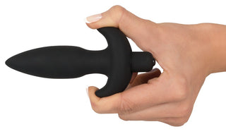 En välvårdad hand med neutralpolerade naglar håller Black Velvets Ankarplugg, gjord av högkvalitativt silikon. Dess släta, avsmalnande design med en utsvängd bas garanterar säkerhet och komfort mot en vit bakgrund.