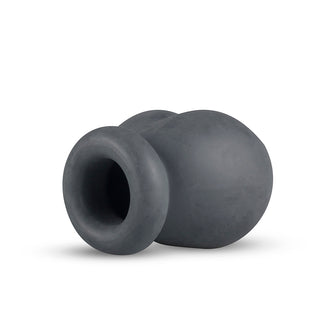 Boners Silikon Ballstretcher är en modern, abstrakt skulptur i mörkgrå keramik med en ihålig, rundad design som påminner om mjuk silikons släta och flexibla karaktär.