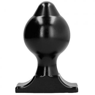 En buttplug, som liknar en svart bondeformad schackpjäs, vilar på en vit bakgrund.