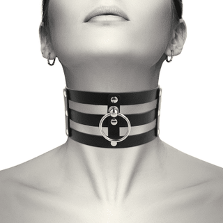 Klädd i "Chocker Med 3 Remmar", en svart vegansk choker i PU-läder med metallringar och dubbar, blickar personen lätt uppåt.