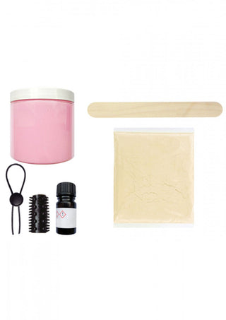 En rosa burk, träpinne, pulverpaket, flaska, svart ring och svart borsthuvud vilar på en vit yta. Dessa är komponenter i Cloneboy Personal Dildo-kit för att skapa din egen klon med hudvänligt material genom en enkel och njutbar gör-det-själv-process.