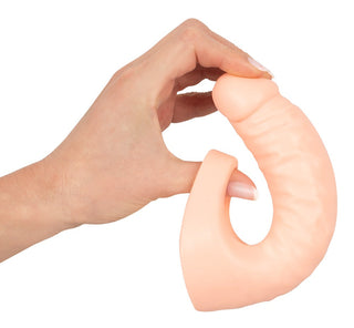 En hand håller den beige, flexibla U-formade Double Trouble Kukring med en rundad ände, sakkunnigt utformad för att förhöja njutningen som en mångsidig sexleksak.