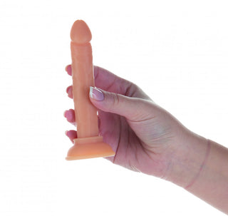 En hand håller i Addiction Dildo Med Sugpropp - 12 cm, ett litet, köttfärgat alternativ med latexvänliga realistiska detaljer, mot en vit bakgrund.