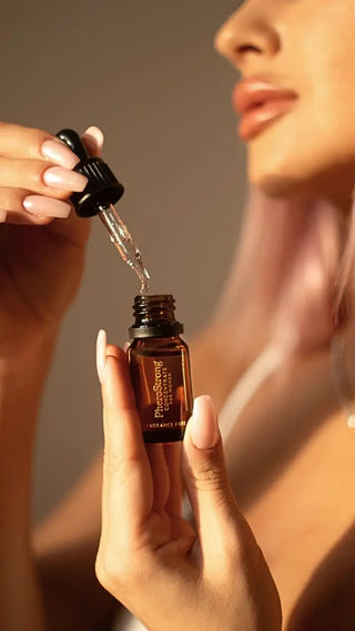 En liten PheroStrong Feromonkoncentrat för Kvinnor-flaska i klarglas med vit etikett och dropplock.