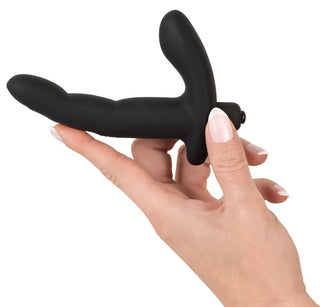 En hand håller en snygg, svart Prostata / G-punkt Vibrator - 13 cm gjord av slät silikon mot en vit bakgrund.