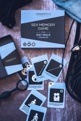 Box och kort för Sex Memory Game Gay Couples, tillsammans med Förspel-tema speltillbehör på en yta.