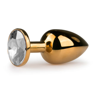 Guld Metall Buttplug - Med Kristall är en lyxig guldfinishad analplugg med en bländande, facetterad kristall vid basen, gnistrande briljant mot en orörd vit bakgrund.