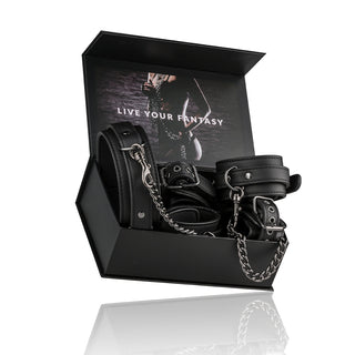 Öppen låda med svarta läderbindningsskydd, kedjor och ett robust "Halsband med fot- och handbojor", allt märkt Live Your Fantasy.