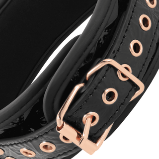 Närbild av BegMe Halsband Med Koppel, ett svart veganskt läderband med roséguld nickelfri metallbeslag inklusive ett spänne och cirkulära genomföringar. Dess blanka exteriör kontrasterar vackert med den matta interiören för en elegant och stilren design.