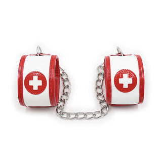 Ohmama 3-delade Nurse Bondage Set innehåller röda och vita manschetter sammanlänkade med en metallkedja, var och en prydd med röda cirklar och vita kors, vilket skapar ett medicinskt tema som är idealiskt för rollspel eller fetischlek som sjuksköterska. Perfekt för att tillföra spänning till fantasifulla äventyr.