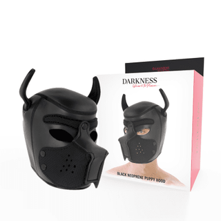 The Darkness Neoprene Hundmask, en svart valphuva i neopren med spetsiga öron och munkorg, visas med en förpackning som visar någon som bär den. Varumärket "Darkness" lyfts fram och tilltalar dem som är intresserade av BDSM-lekar.