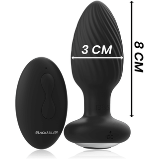 Black&Silver Wells Fjärrstyrd Buttplug, tillverkad av kroppsvänlig silikon och har en strukturerad yta, är 3 cm bred och 8 cm hög. Den innehåller en trådlös fjärrkontroll och båda visas på en ren vit bakgrund.