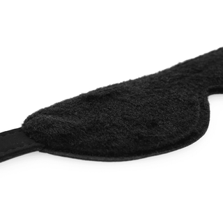 Närbild av Intense Vegansk Ögonmask, en svart fuzzy vegansk ögonmask gjord av veganskt läder med justerbart elastiskt band, visad mot en vit bakgrund.