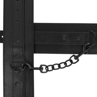 Ankelmanschetter i svart läder med nitar, sammanfogade med en kort metallkedja och clips.