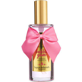 Klar flaska Bijoux Indiscrets Massageolja Bubblegum med guldlock och rosa rosett, med en lekfull bubbelgumssmak för söta stunder.