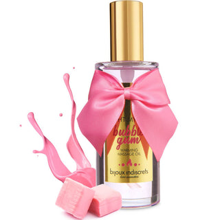 Klar flaska Bijoux Indiscrets Massageolja Bubblegum med en rosa rosett, rosa vätskestänk och tuggummibitar - njut av ätbar massageolja med utsökt tuggummismak.
