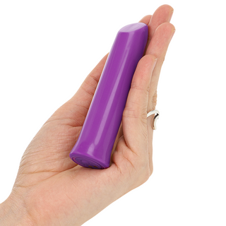 En hand håller i Lila Klitorisbullet Todrick, en liten, lila cylinderformad klitorisstimulator med rundad topp, tillverkad av medicinsk silikon.