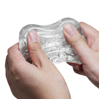 Klar, texturerad masturbator med två ändar tillverkad av transparent material, visad mot en vit bakgrund.