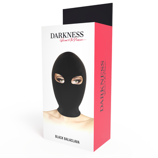 På förpackningen till Darkness Submission Mask Black, märkt DARKNESS, finns ett foto av en person som bär den svarta masken med ögonöppningar för fri sikt.