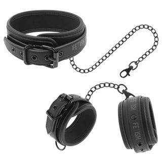 Svart halsband och handledsmanschetter i veganläder med kedjor, spännen och bojor i metall.