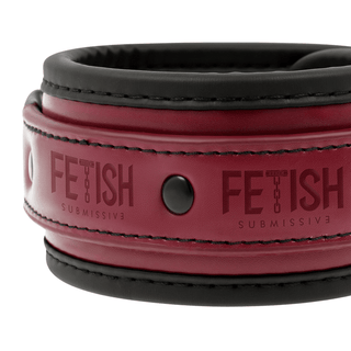 Närbild av en rött och svart läderkrage med nitar märkta Fetish Submissive, en idealisk kombination för BDSM-nybörjare som utforskar nya nöjesriker tillsammans med handbojorna med neoprenfoder.