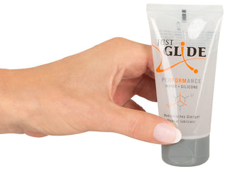 En hand håller en tub med Just Glide Performance, med en hybridformel som blandar vatten och silikon för långvarig jämnhet, vilket säkerställer optimal komfort och prestanda.