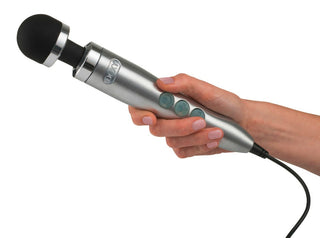En Die Cast 3 Doxy Wand med ett svart rundat huvud och tre krickfärgade knappar visas i en ljushyad hand. Denna eleganta handhållna massageapparat i silver, en sladdad enhet, erbjuder vibrationsinställningar i flera hastigheter för anpassningsbara avslappningsupplevelser.