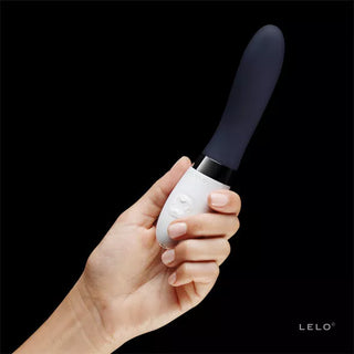 En hand håller LELO Liv 2, en svartvit vibrator designad för G-punktsstimulering, mot en svart bakgrund.