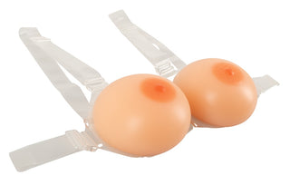 Harness Silikon Bröst är en nyhet BH med plastband och två runda, kötttonade inlägg designade för att efterlikna naturliga bröstvårtor för en sömlös look.