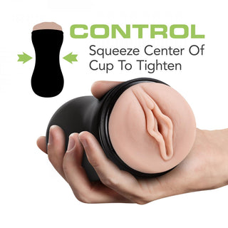 En hand håller en svart squeeze cup med en hudtonad öppning, märkt Control: Squeeze Center Of Cup To Tighten, idealisk för användning med vattenbaserat glidmedel för ökad komfort och njutning. Produkt: Soft + Wet Pussy Lösvagina.