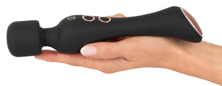 En hand håller en svart vattentät handhållen massageapparat med knappkontroller, liknande Warming Magic Wand.