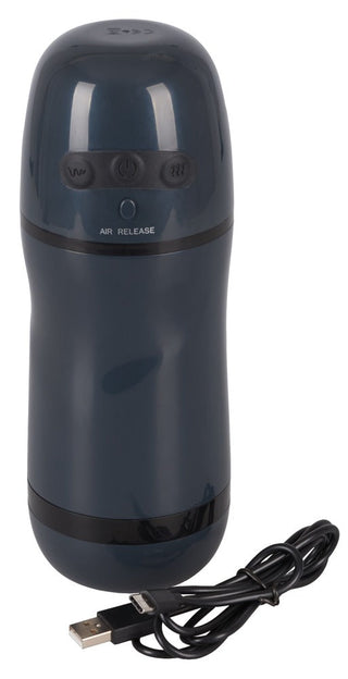 Sugande Effekt Masturbator - Rebel, en mörkgrå cylindrisk enhet med knappar som liknar en elegant vibrator, är placerad bredvid en svart USB-kabel.