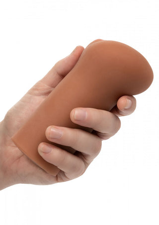 En hand håller ett köttfärgat Lösvagina Cheap Thrills, ett Pure Skin cylindriskt föremål med en rundad topp, mot en vit bakgrund.