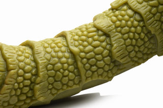 En närbild av en grön texturerad tentakelleksak gjord av högkvalitativt silikon visar fjällande mönster och åsar, som liknar en Swamp Monster Dildo, på en vanlig vit bakgrund.