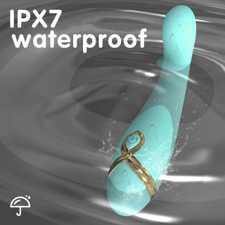 Teal G-spot vibrator med guldband, slät silikonfinish, visas i vatten. IPX7 vattentäthetsklassning och paraplyikon synlig.