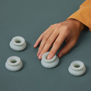En hand rör mjukt en av fyra OHNUT - Classic Soft Buffer Rings på en grön yta, varje ring ger unik komfort och stöd.