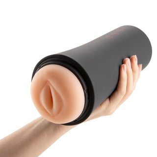 En hand håller elegant OTouch Inscup 2 lyx masturbator, en svart cylindrisk vuxenleksak med en mjuk beige öppning. Denna sofistikerade enhet erbjuder handsfree-njutning och förbättrar upplevelsen med sin diskreta design.