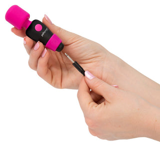 Händer som håller en liten svart och rosa Palm Power - Pocket Wand-enhet med en avtagbar metallspets, designad för maximal komfort med sitt flexibla huvud.