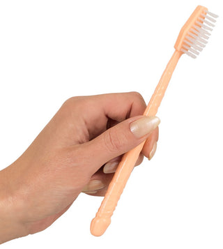 En hand håller en ljus persikofärgad Penis Formad Tandborste med vita borst mot en vanlig vit bakgrund, som utstrålar diskret elegans.