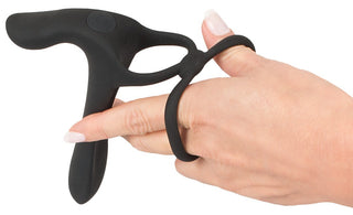 En hand håller den eleganta svarta Penisring Couples Vibratorn, tillverkad av silikon med öglor för enkelt grepp, designad för att fungera som en effektiv klitorisstimulator.